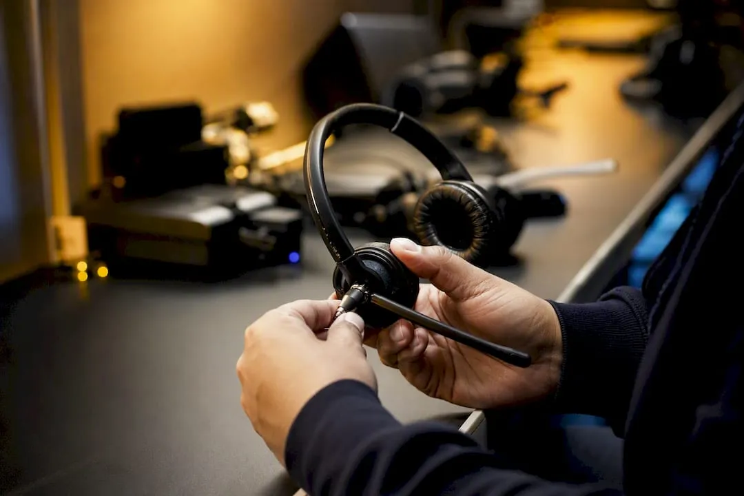 Manos ajustando el micrófono de un auricular telefónico